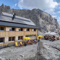 Totalphütte mit Terrasse und Wanderer auf Sonnenliegen.